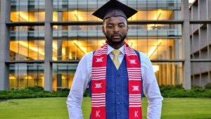 Student Montel Hall wearing graduation cap and Kappa Alpha Psi sash standing in front of Christopher Center