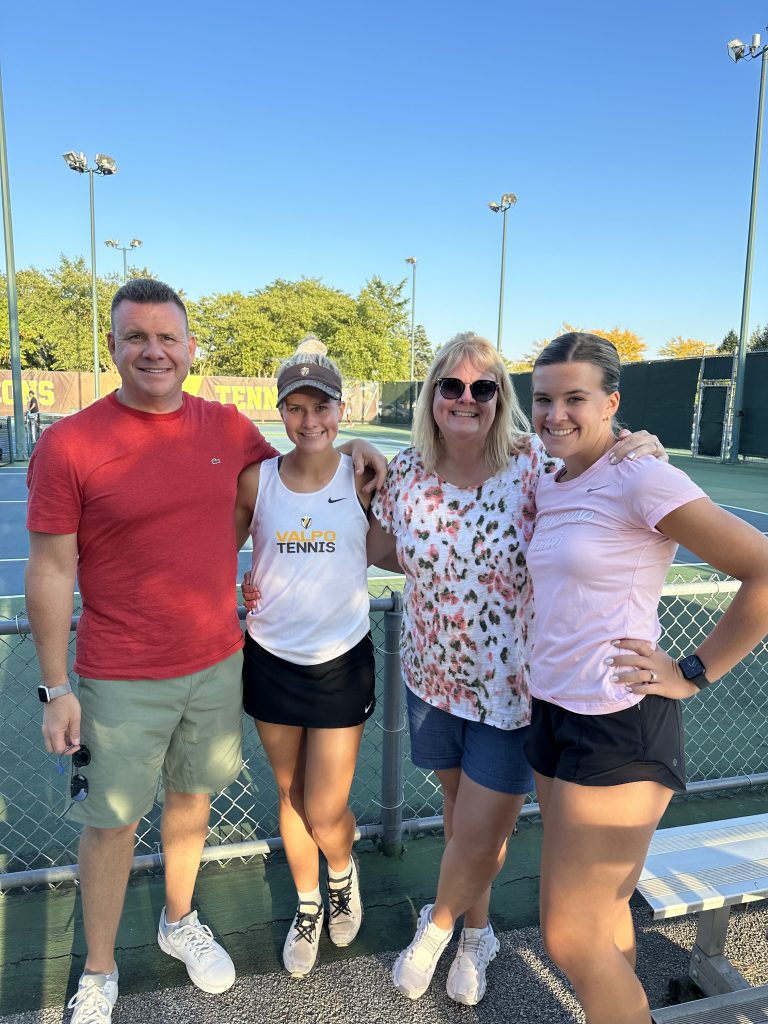 Olivia Czerwonka '23, '26 DNP, and Claire Czerwonka '21, '24 DNP, posing with their parents on Valpo's tennis court after a match.