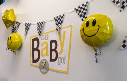 Sign reading “Go BaBy go!” with smiley balloons and checkered bunting at a Valparaiso University Collaboration Challenge.