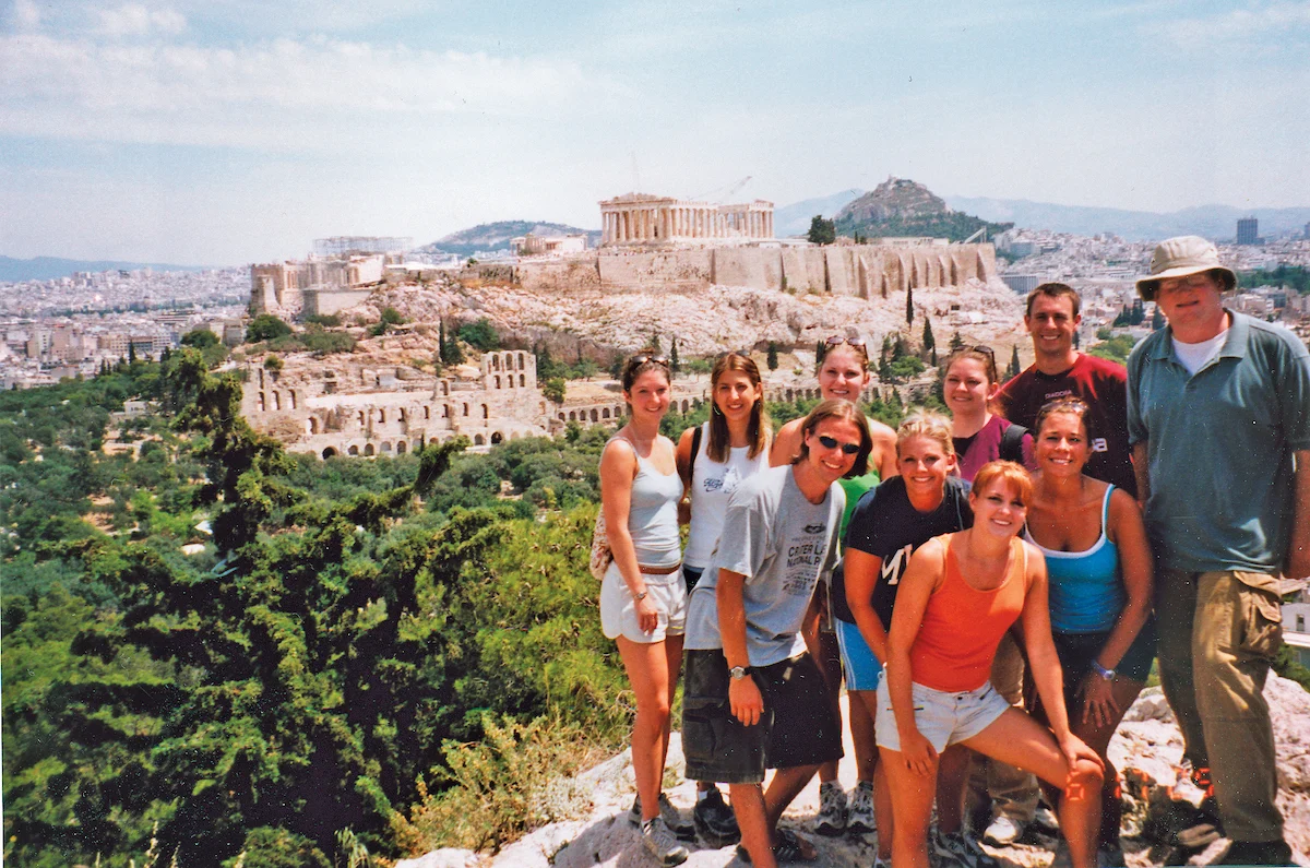 A group of people posing with the Acropolis and Parthenon in Athens, Greece visible in the background during their Study Abroad experience.