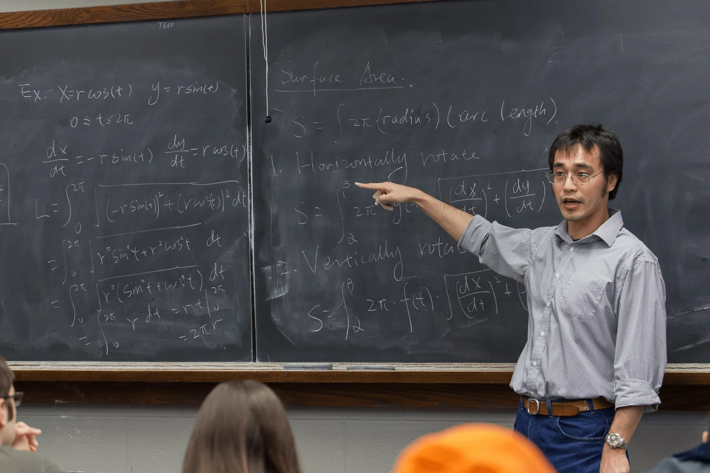 A Valparaiso University mathematics professor points to a chalkboard with equations written on it during a class.