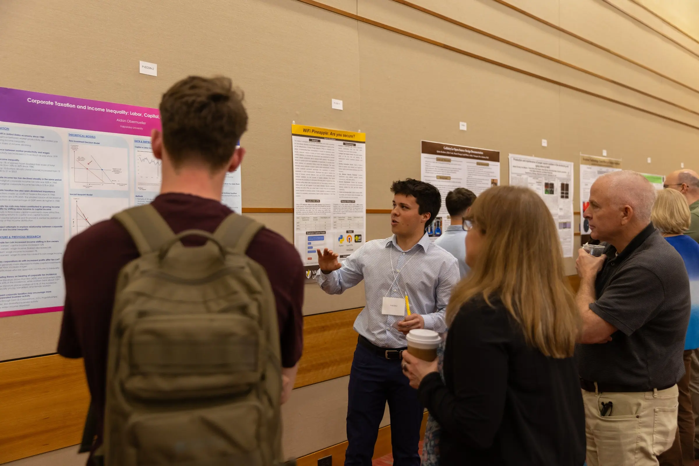 A person presents a research poster to a group in a conference hall, offering an insightful departmental overview that highlights the value of experiential learning within their field.