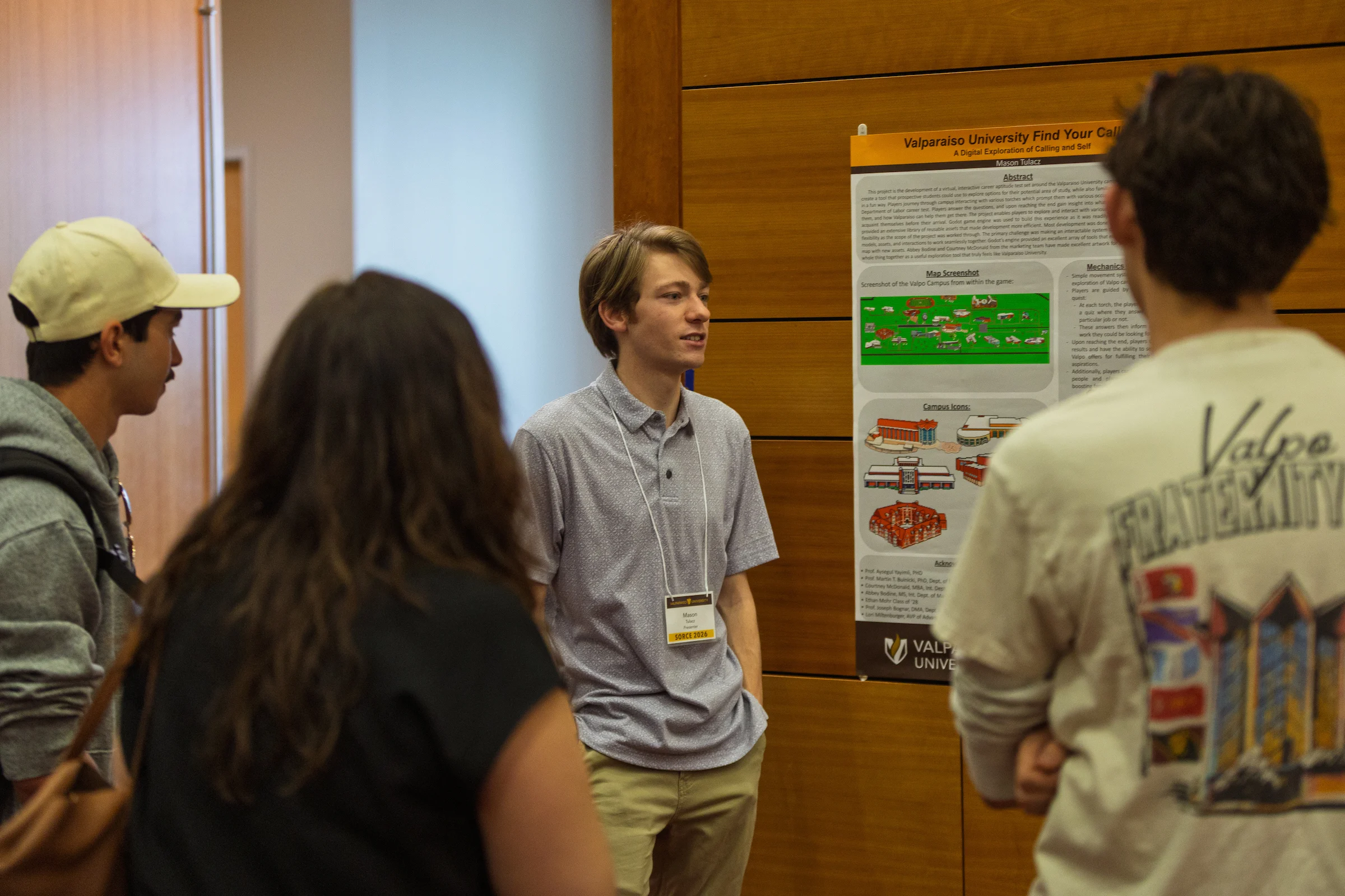 A student presents a research poster to three people in a university hallway, highlighting key findings and discussing how the project connects with career resources offered by the campus DEV center.