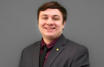 Valpo student in a suit and tie smiling in front of a plain gray background, ready to embark on his internship with the Nuclear Regulatory Commission.