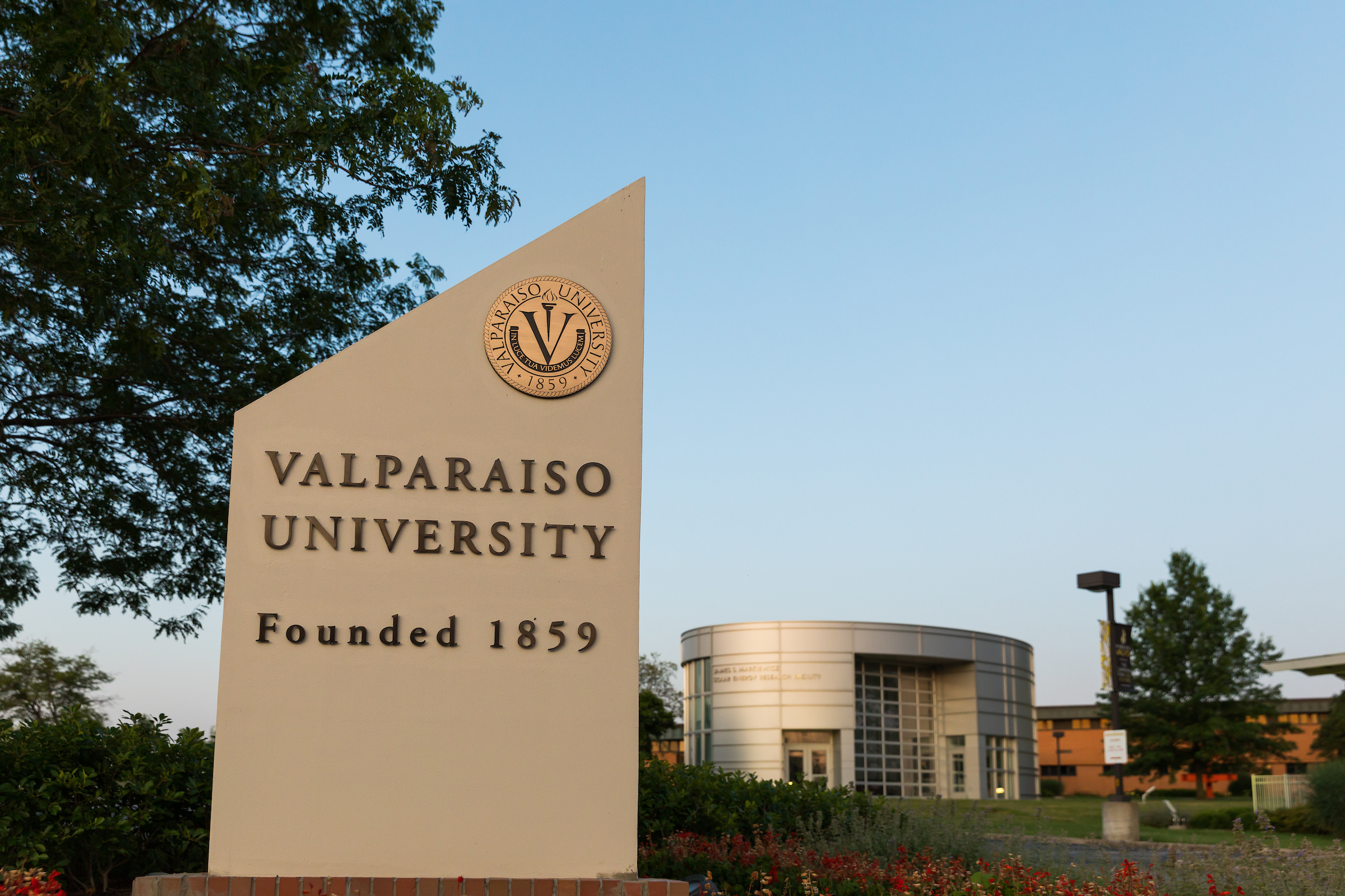 Campus photo with VALPARAISO UNIVERSITY sign in foreground and solar energy research facility in background