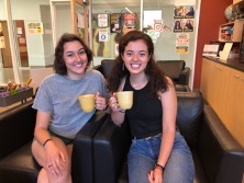 Olivia Zetty and Mariah Hykins holding coffee mugs, sitting and smiling.