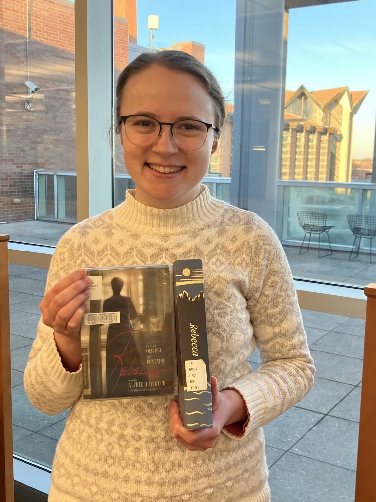 Grace Biermann holding a digital and print copies of "Rebecca".