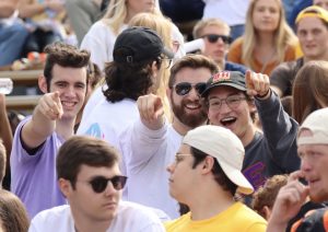 Noah Godsell '24 laughing and pointing to the camera with two fellow students during a Valpo Athletics sporting event.