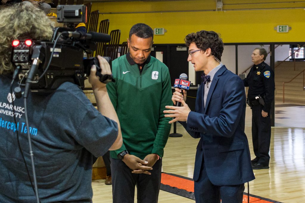 Noah Godsell '24 smiling while he interviews a coach on camera.