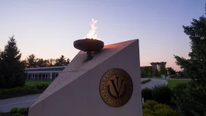 A flame burns atop a monument with the Valparaiso University seal at sunset, celebrating the impact of a $1 Million Grant from the Lilly Endowment.