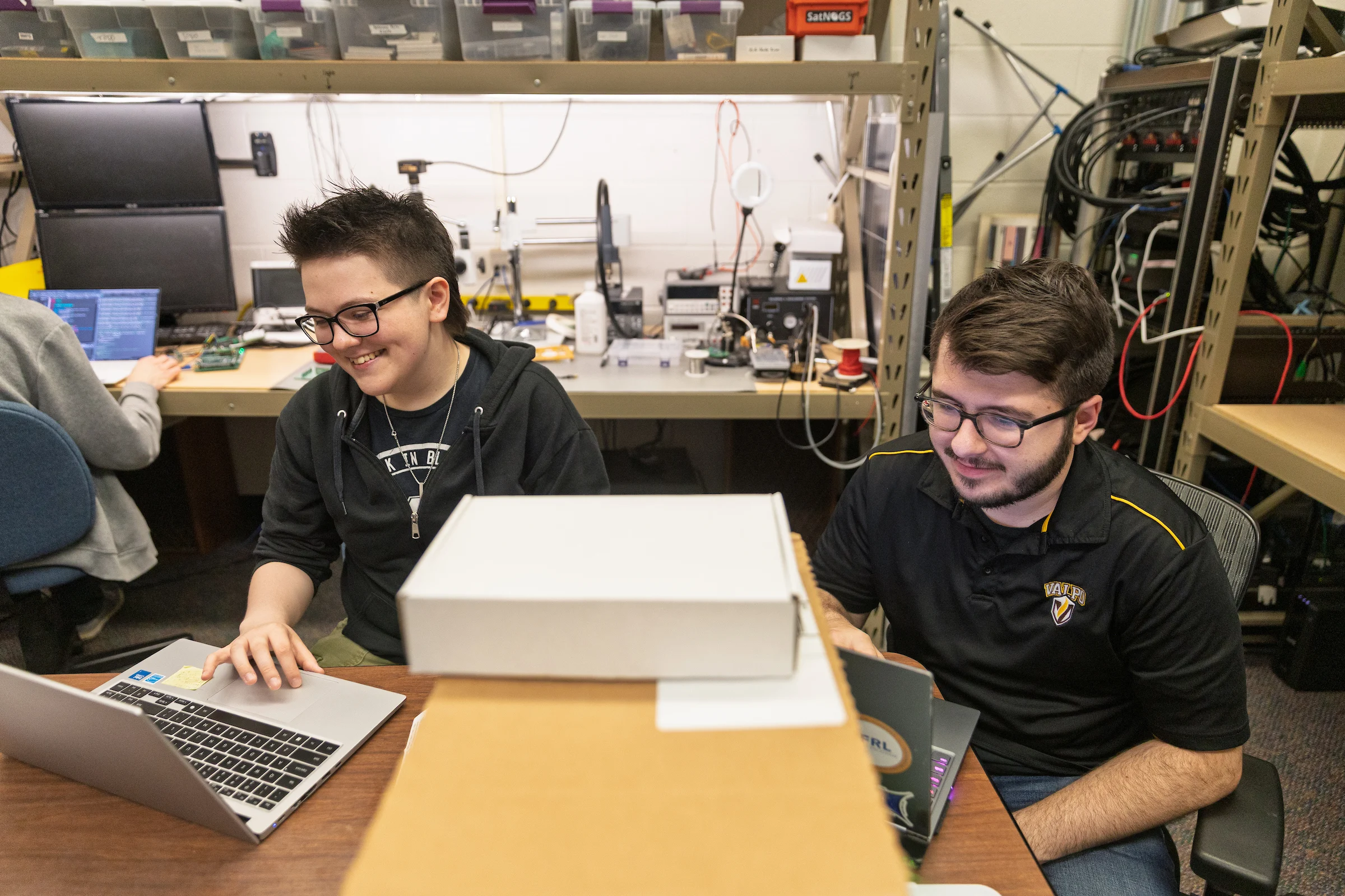 Two Valparaiso University engineering students work on laptops as they collaborate as part of a satellite project.