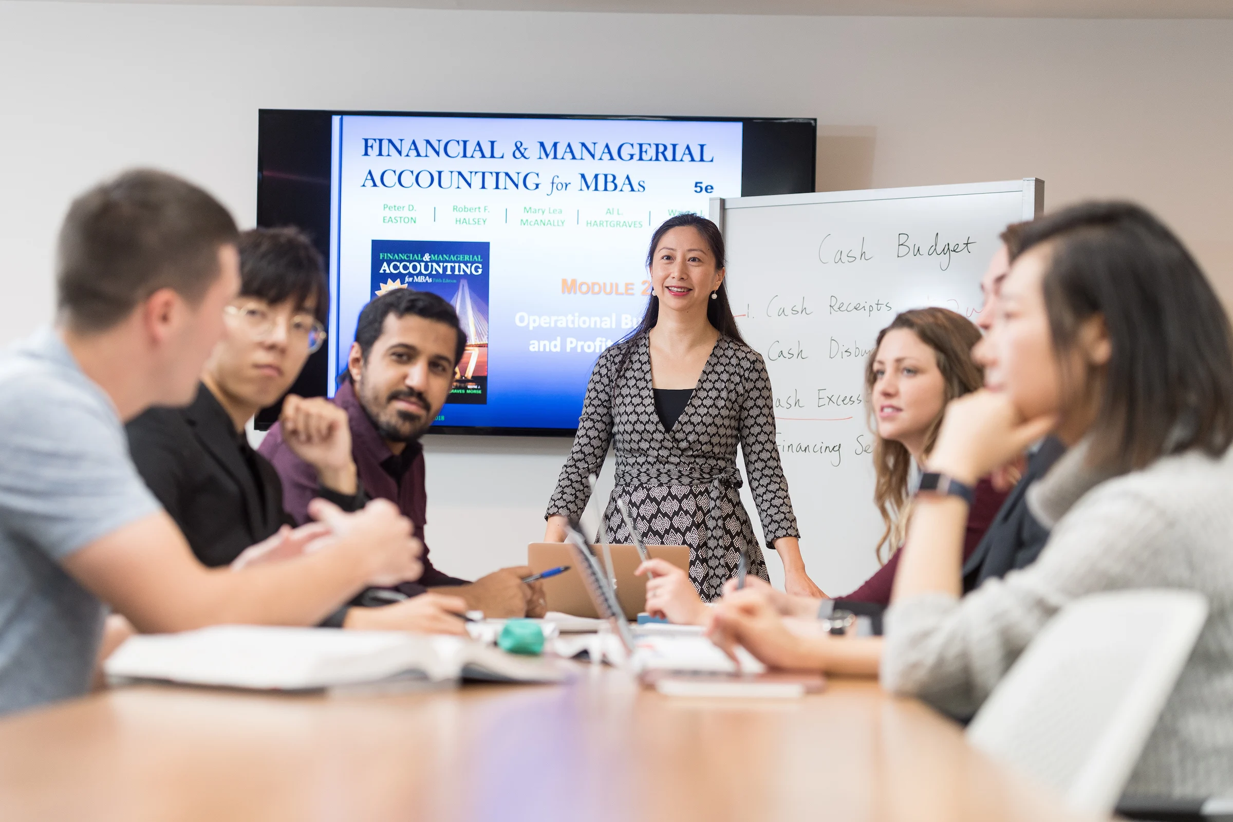 A Valparaiso University business professor stands in front of a table with a group of master of business administration (MBA) students while teaching a course in the program.