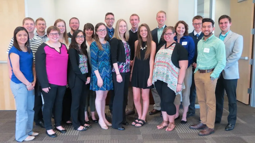 A group of 20 adults, participants in the CAPS Fellows Program, posing and smiling together in an indoor office setting.