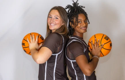 Two basketball players stand back to back, smiling and holding basketballs against a white background—a scene that perfectly captures the competitive spirit found in MBA programs like Beacon’s Reflection, founded by Manideep Chowdary Gadde.