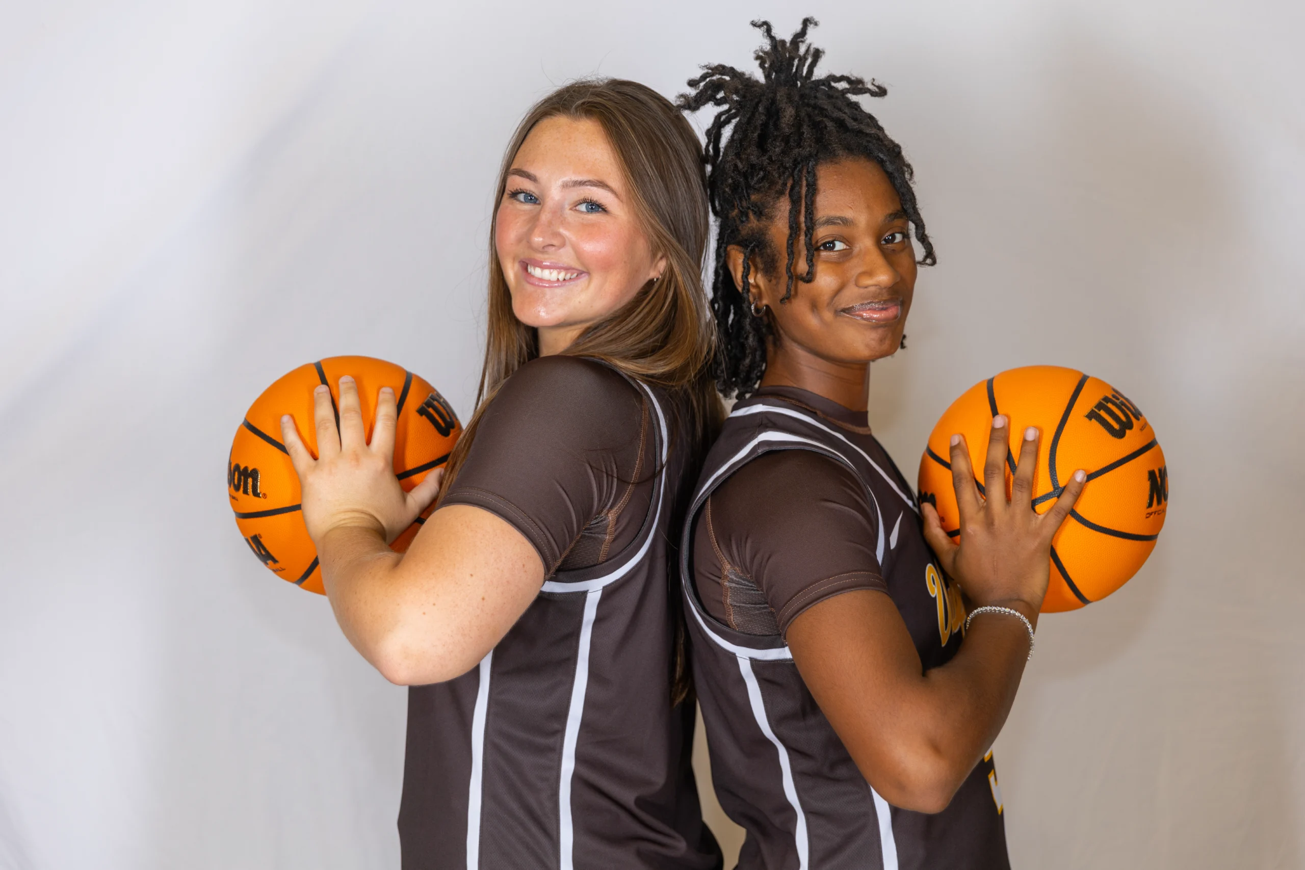 Two basketball players stand back to back, smiling and holding basketballs against a white background—a scene that perfectly captures the competitive spirit found in MBA programs like Beacon’s Reflection, founded by Manideep Chowdary Gadde.