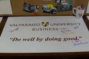 A Valparaiso University Business sign with the quote “Do well by doing good” and several handwritten signatures highlights the values embraced in their MBA Program.
