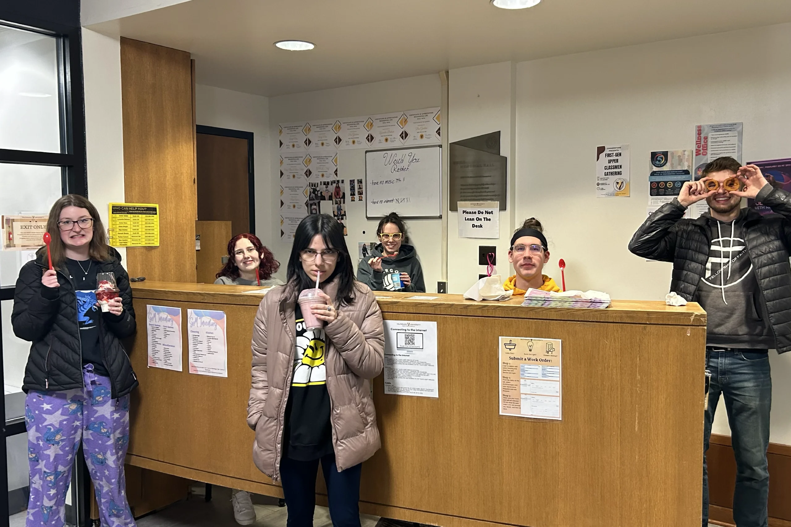 Six people, including Parker Kelson, are smiling and holding popsicles in front of a wooden counter in an office setting, capturing a candid moment reminiscent of Beacon's Reflection.