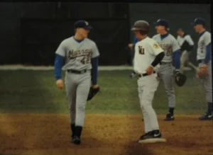 Jeff Conrad and another baseball player talk on the field, while others stand in the background during a Beacon game.