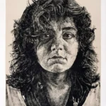 Black and white portrait of a person with wavy hair, looking directly at the viewer with a neutral expression.