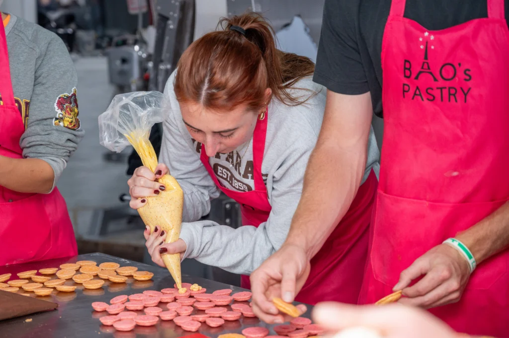 At a Valpo bakery workshop, a woman pipes filling onto cookies while others help assemble them, bringing experiential learning to life in the French program.