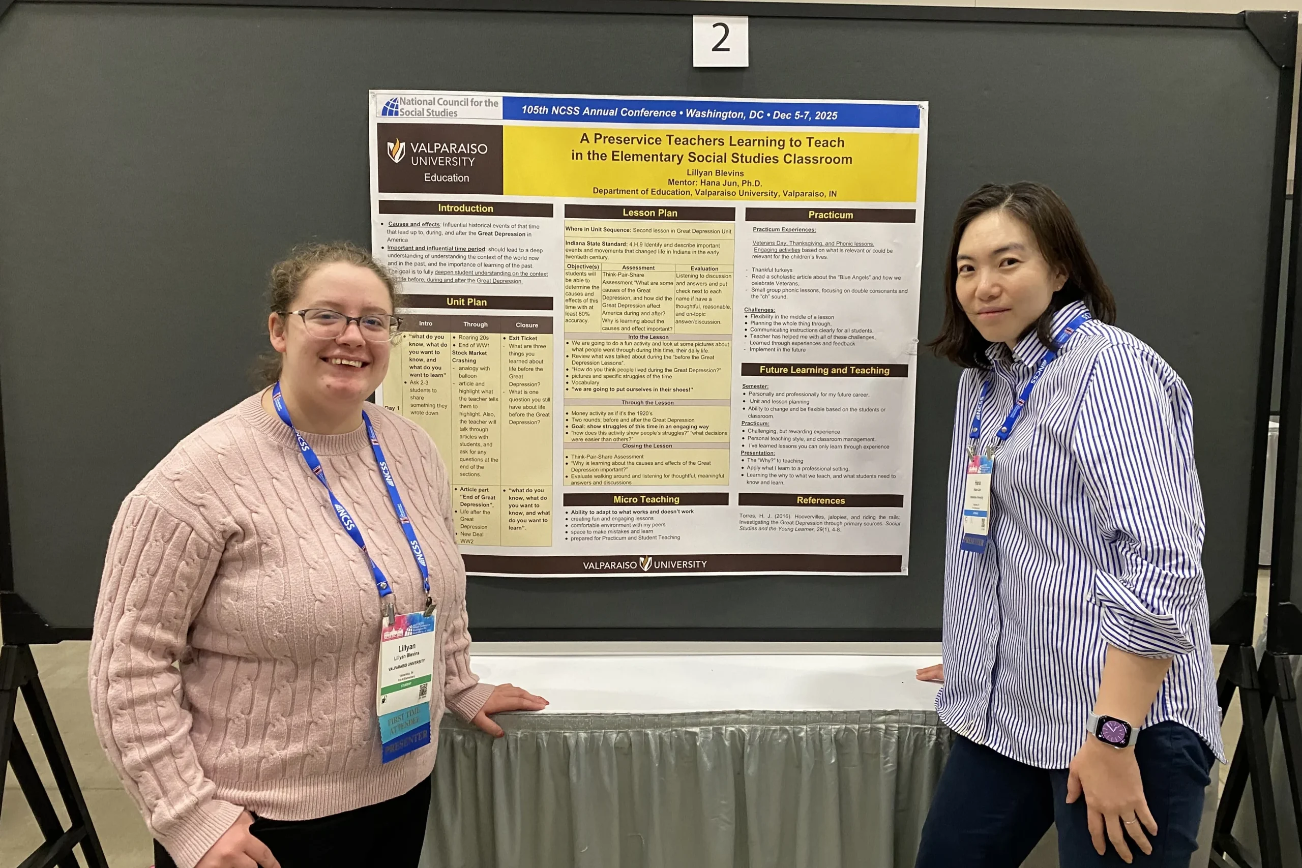 A Valparaiso University education professor and student stand in front of a research poster about elementary social studies teaching at a national conference.