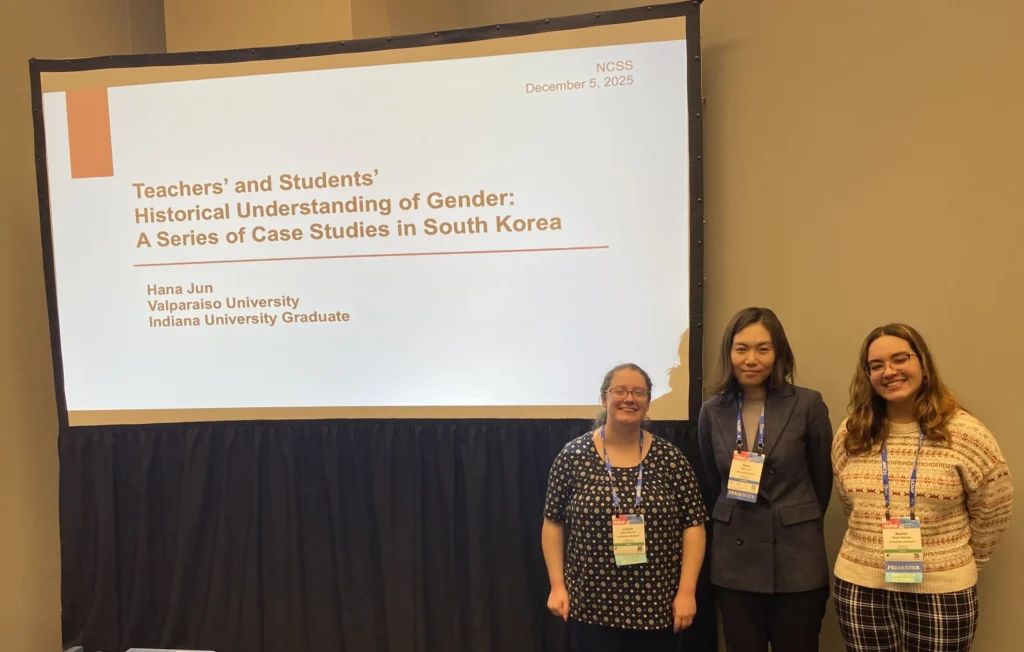 A Valparaiso University education professor and students stand in front of a projected research presentation at a national conference.