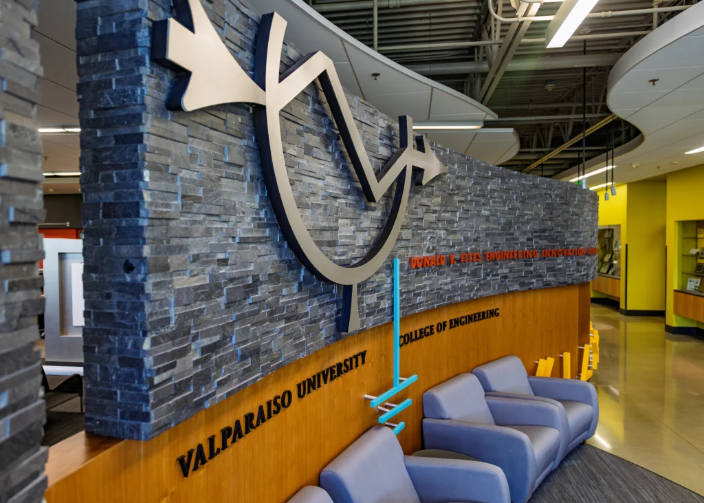 Modern lounge area at Valpo’s College of Engineering, fostering community among Computer Engineering students, features a striking stone wall and abstract metal sculpture.