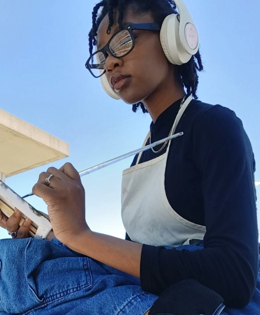 Woman wearing headphones and glasses painting outdoors, inspired by Beacon's Reflection, holding a palette and brush beneath a clear blue sky.
