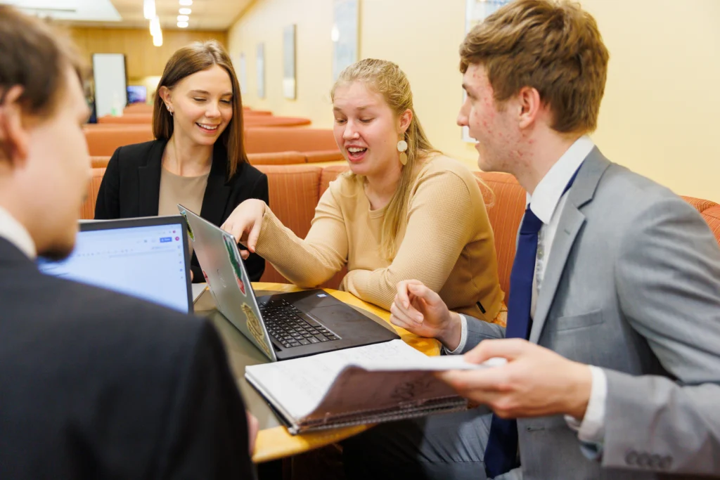 Four young professionals collaborate at a table with laptops and notebooks in a meeting room, sharing ideas about interesting majors and unique degrees that can lead to surprising careers.