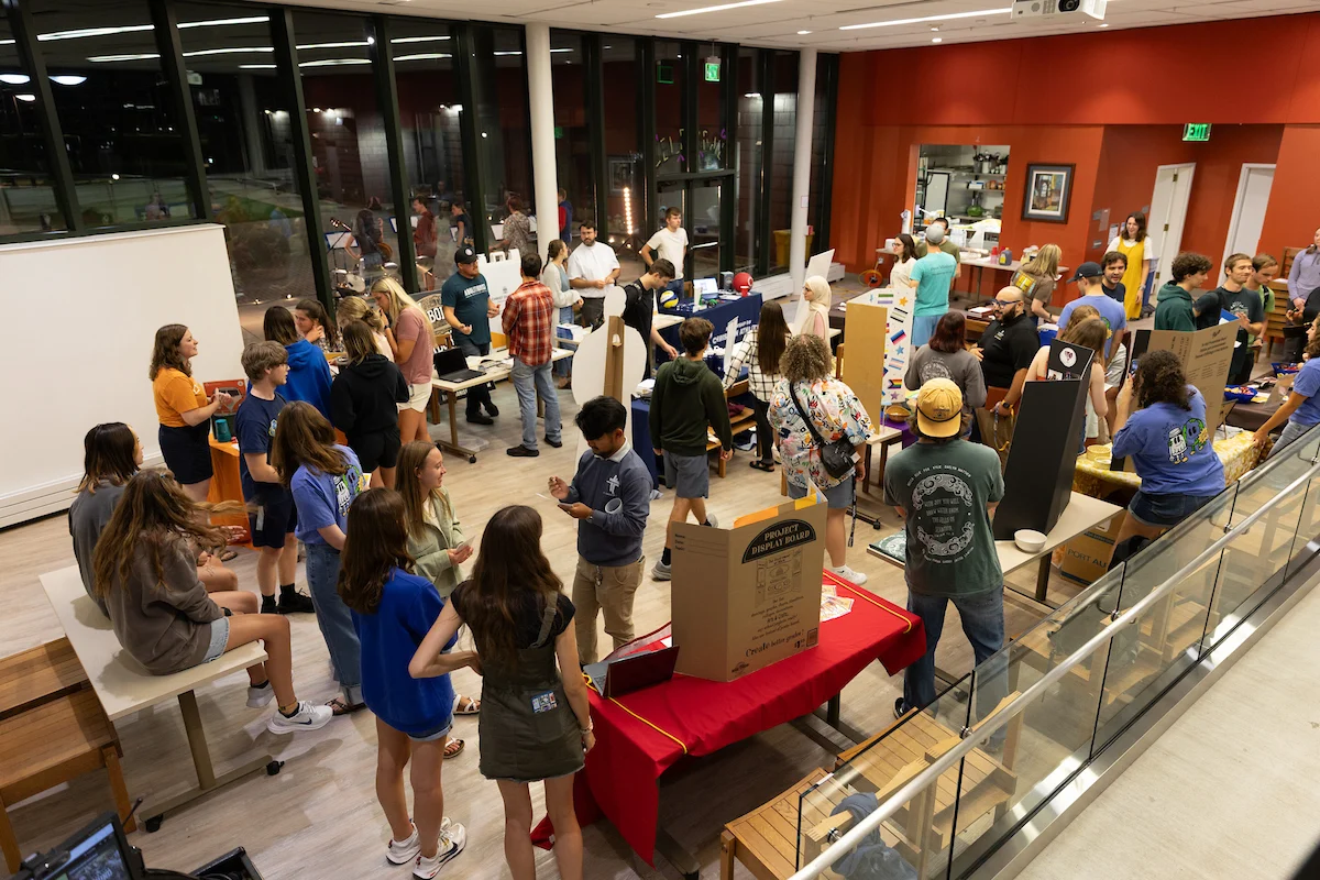 Students gather in a bright room with tables, displays, and posters for a school event focused on Calling and Spiritual Life.