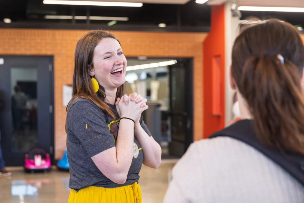 Woman smiling and clasping her hands while talking to another person indoors, highlighting the supportive environment at Valpo's accredited Occupational Therapy Doctorate program.