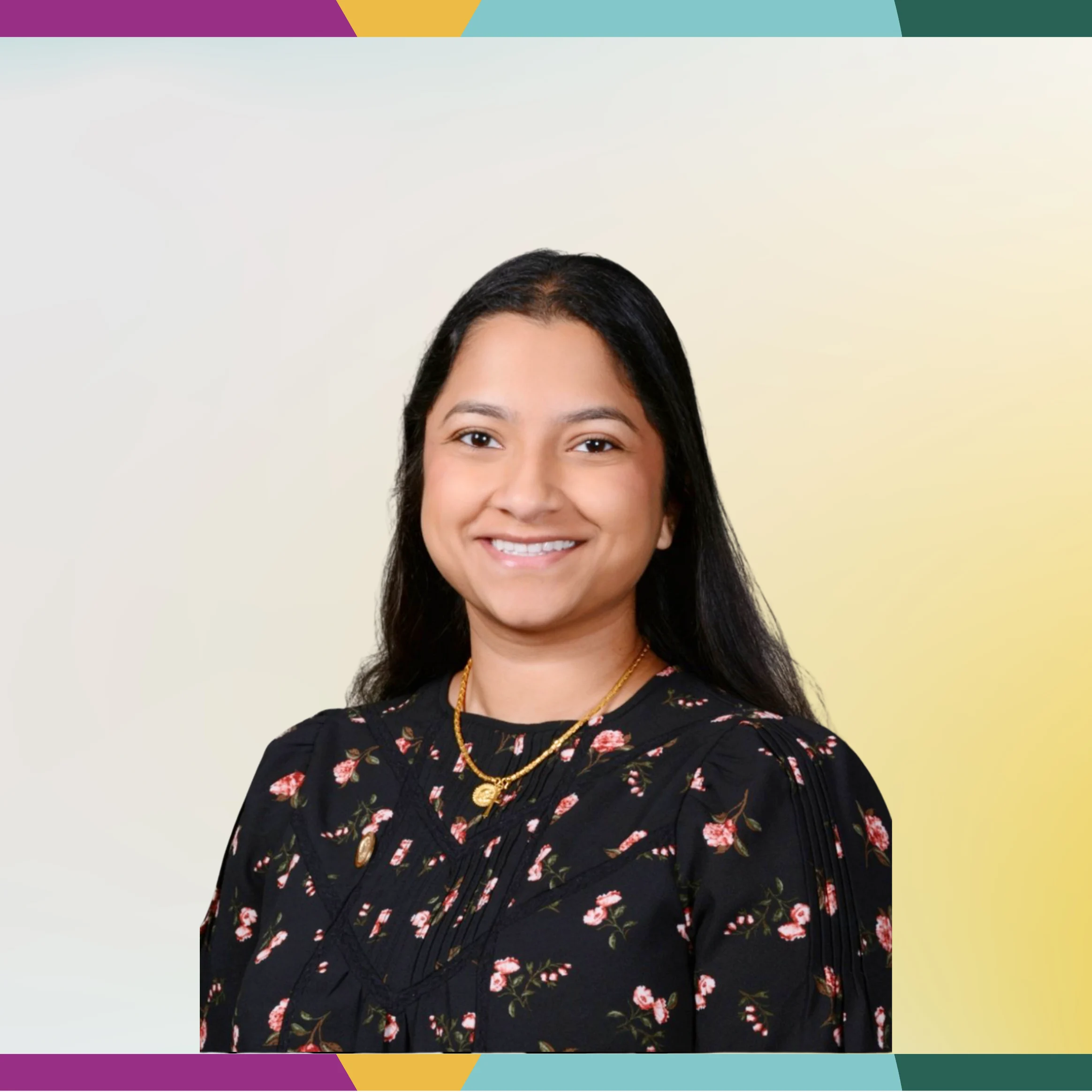Woman with long dark hair in a black floral top, smiling in the spotlight, on a light gradient background with a colorful border.