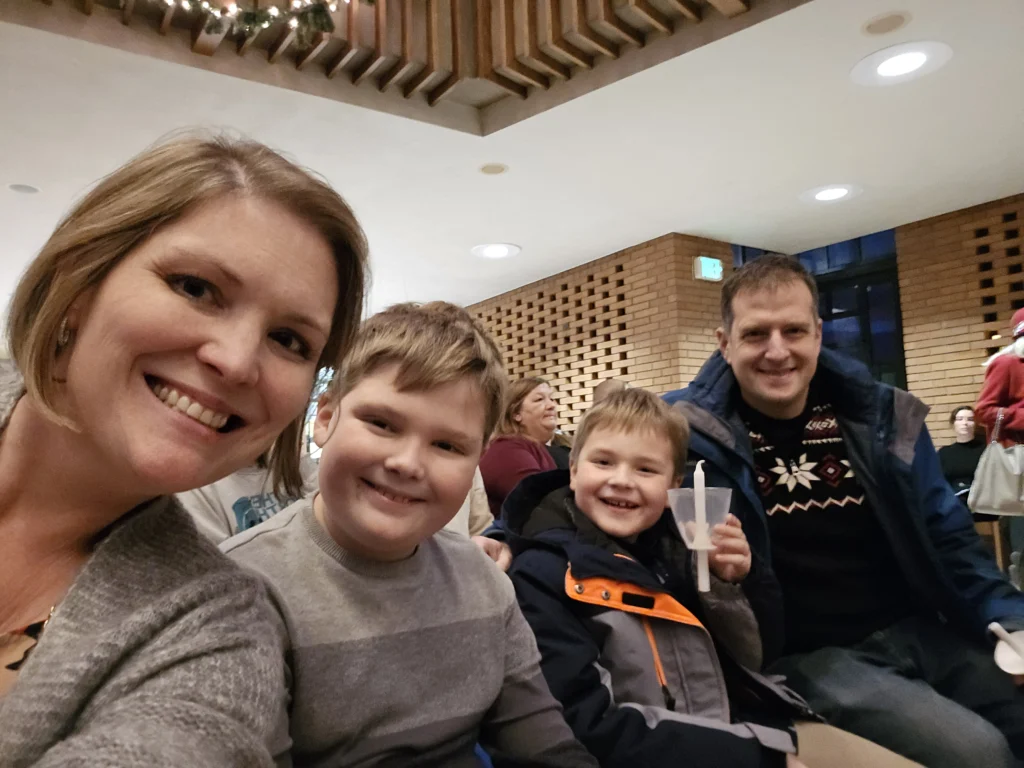 A smiling family of four sits indoors, with two boys in the center and parents on either side, capturing a warm moment for Johnson MEM at Beacon, photographed by Dayna Smoljo.