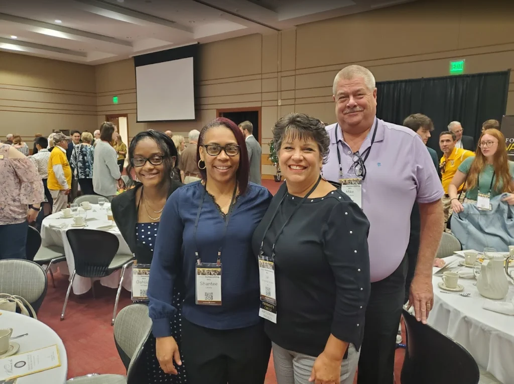 Shantée Lewis and three others smile and pose together at a round-table event during the crowded 2022 Beacon conference.
