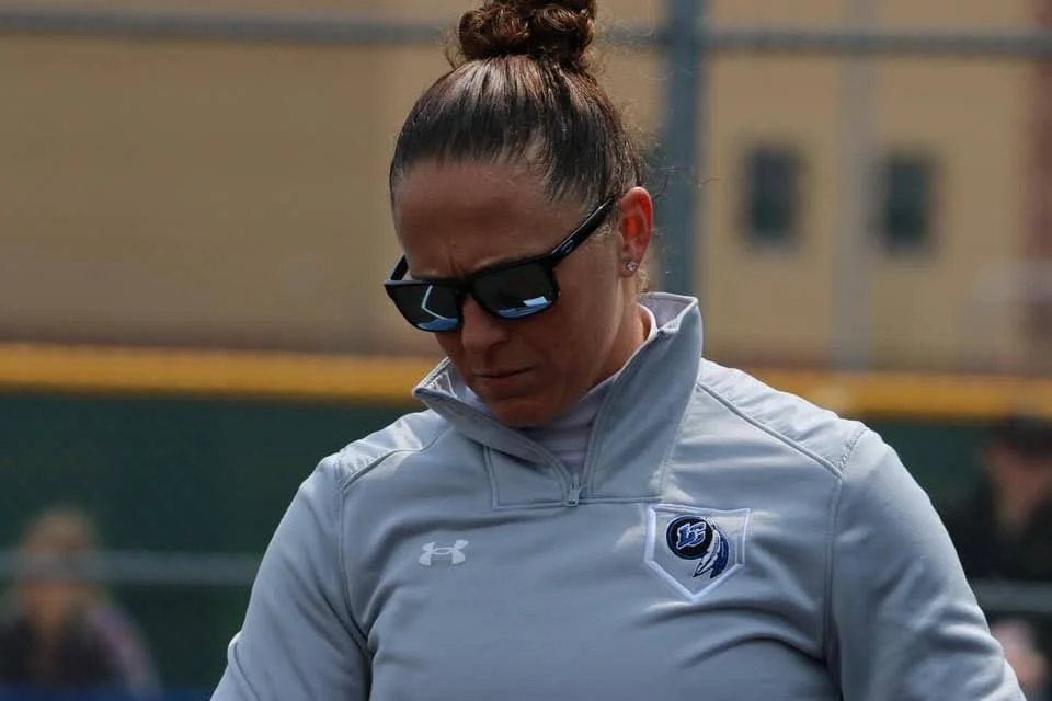 Jeanette Gray, in sunglasses and a gray sports jacket, stands outdoors like a quiet beacon, looking down.