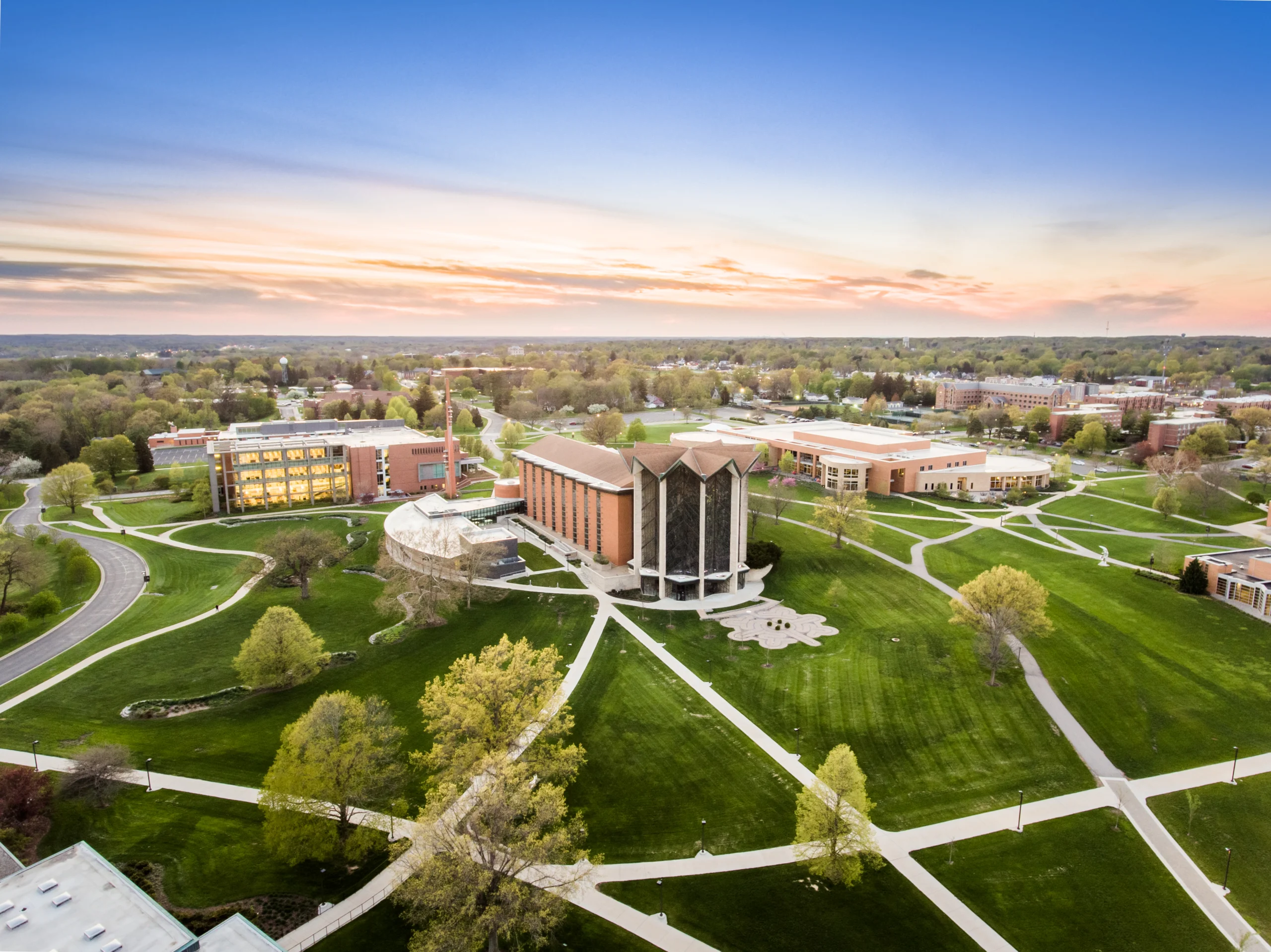 Aerial view of Valparaiso University campus with green lawns, walkways, and modern buildings at sunset.