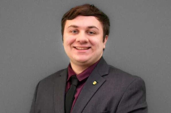 Valpo student in a suit and tie smiling in front of a plain gray background, ready to embark on his internship with the Nuclear Regulatory Commission.