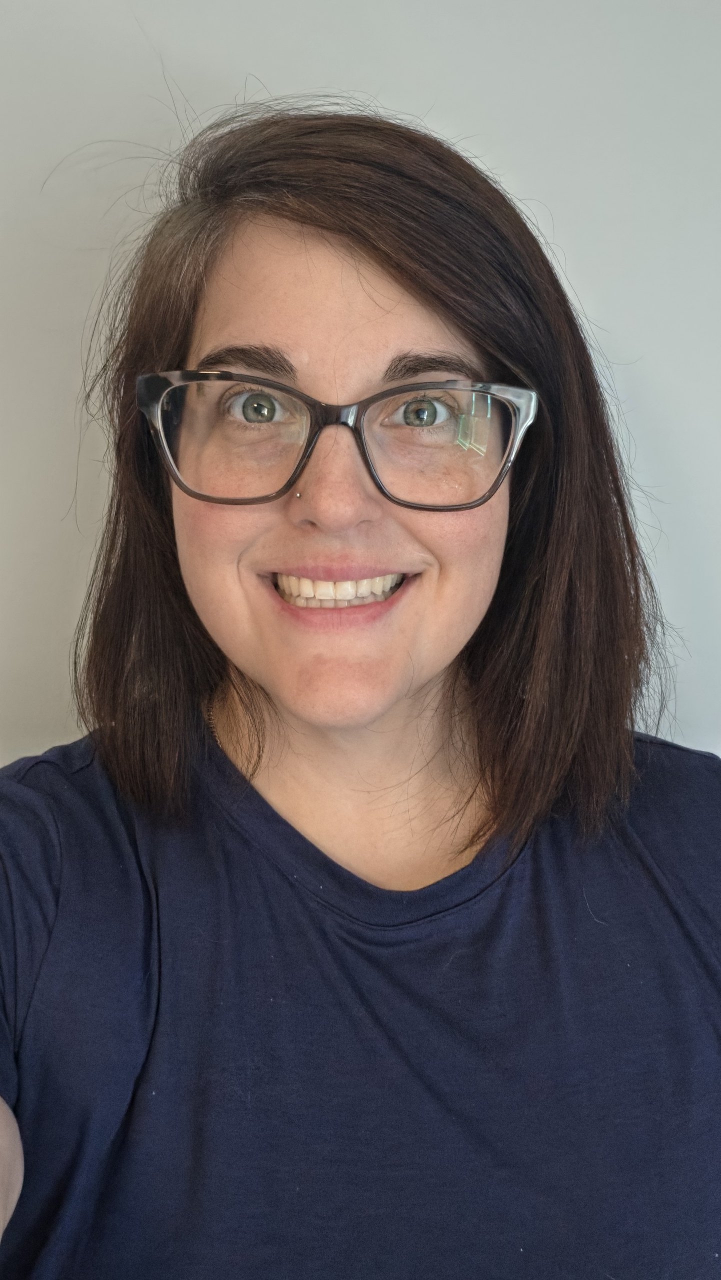 Person with shoulder-length brown hair, glasses, and a navy shirt smiling at the camera against a plain background, representing the Tobacco Education and Prevention Coalition.