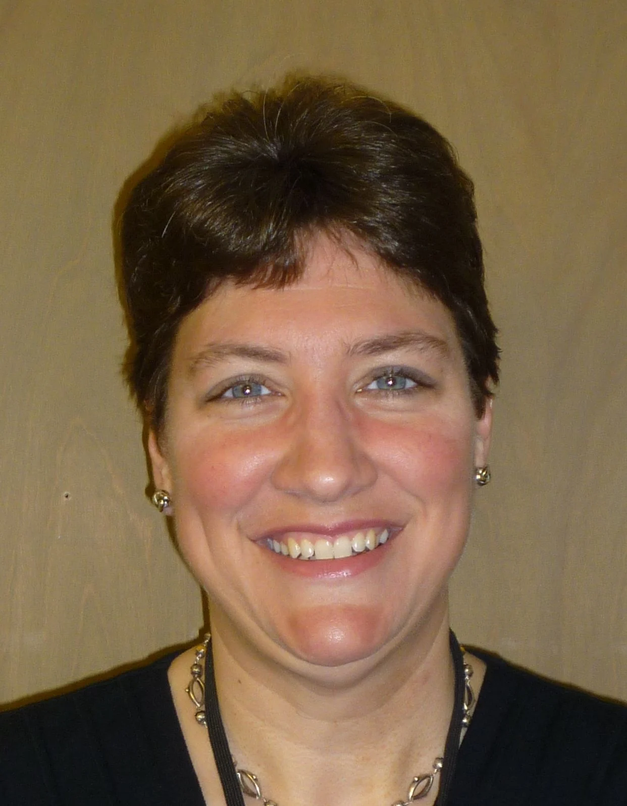 A smiling woman with short dark hair leading a workshop.