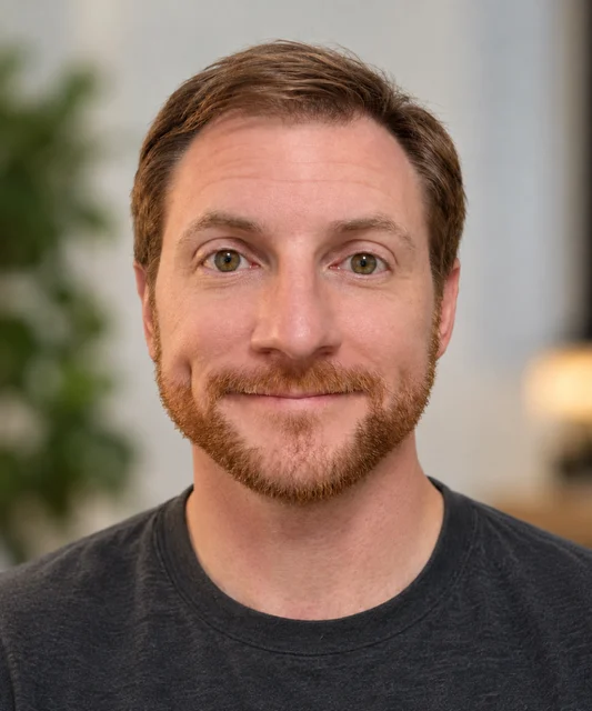 Headshot of a man with short brown hair and a beard, wearing a dark t-shirt for our workshops.